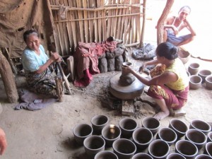 A village dedicated to making pots. The lady on the left pumps the wheel for the potter.